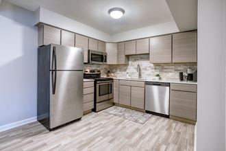 a kitchen with stainless steel appliances and wooden flooring