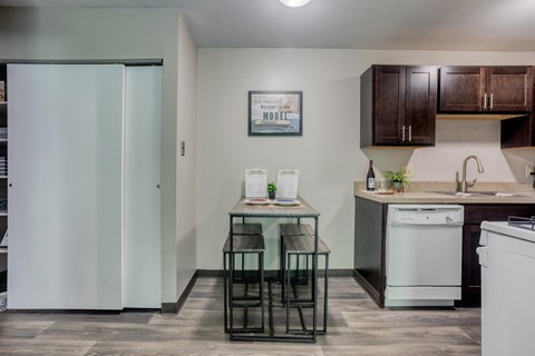 a kitchen with white appliances and a small table with three stools