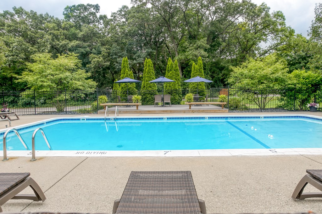 A pool surrounded by trees and umbrellas.