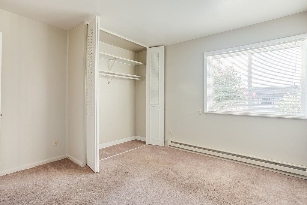a bedroom with a large window and a closet