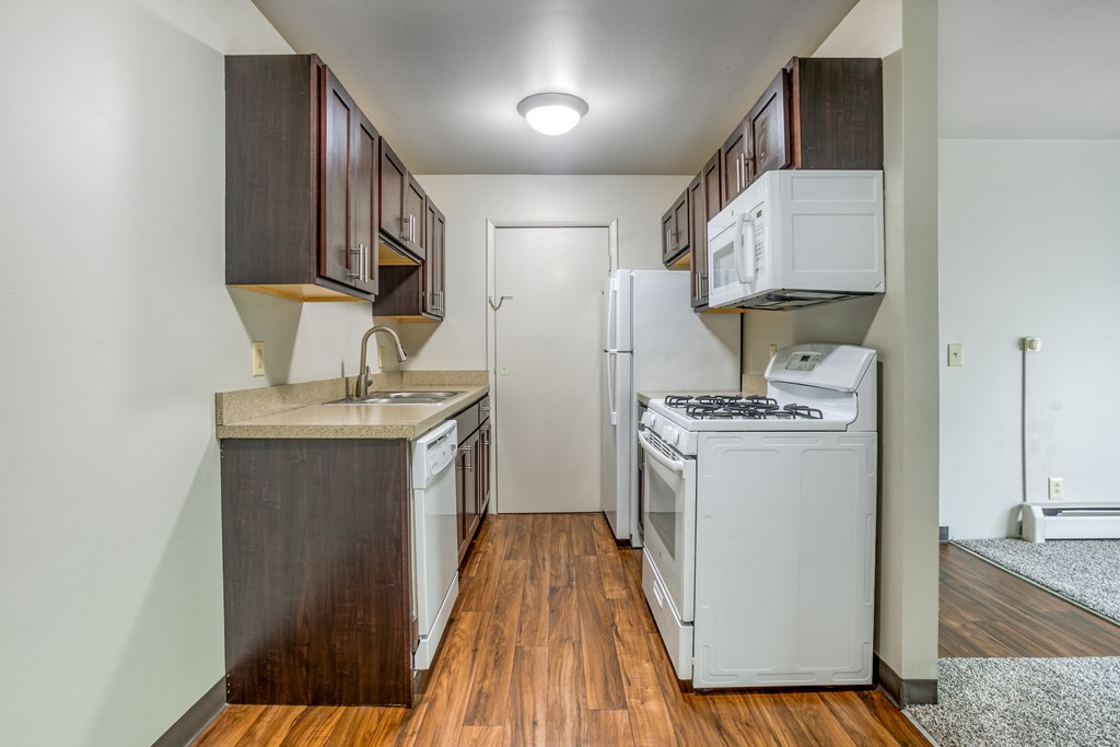 A kitchen with white appliances and wooden cabinets.