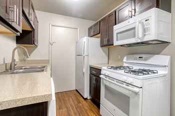 A kitchen with white appliances and brown cabinets.