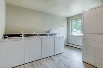 a laundry room with white cabinets and a window