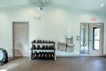 A room with a dumbbell rack and a vacuum cleaner.
