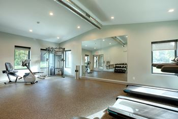 A spacious gym with a treadmill, elliptical machines, and other exercise equipment.