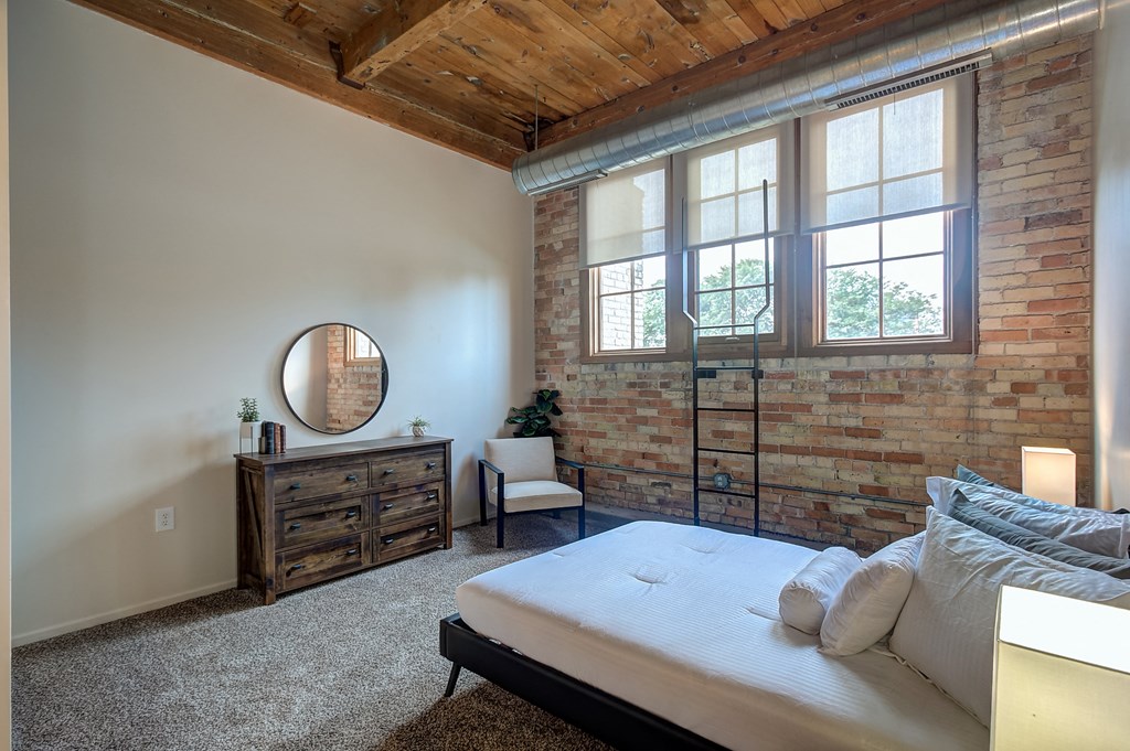 A bedroom with a bed, dresser, and mirror.