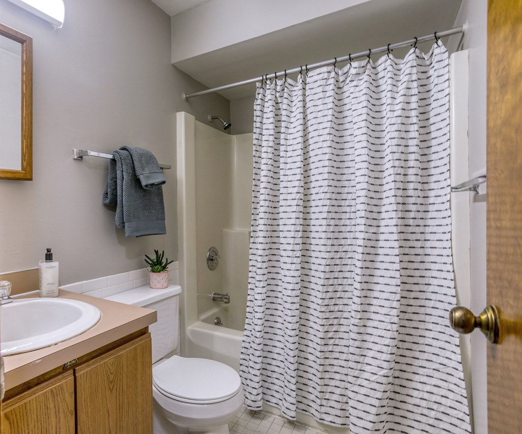 a bathroom with a white sink and toilet and a white shower curtain