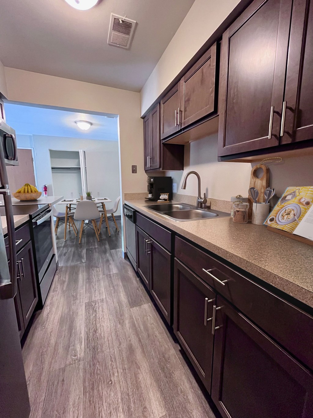 A kitchen with dark wood cabinets and a light brown floor.