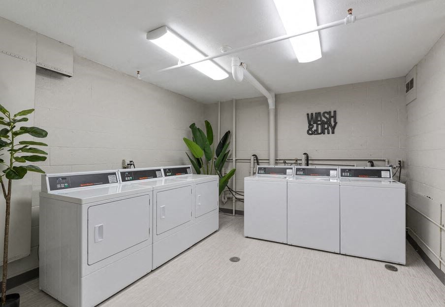 a row of white washers and dryers in a laundry room