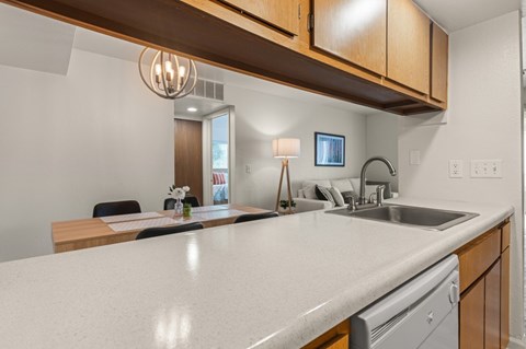 A modern kitchen with a white countertop and wooden cabinets.