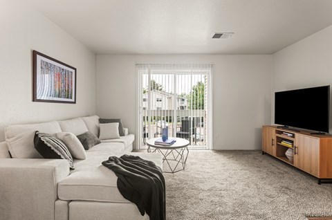 A living room with a white couch, a black blanket, a coffee table, and a television.