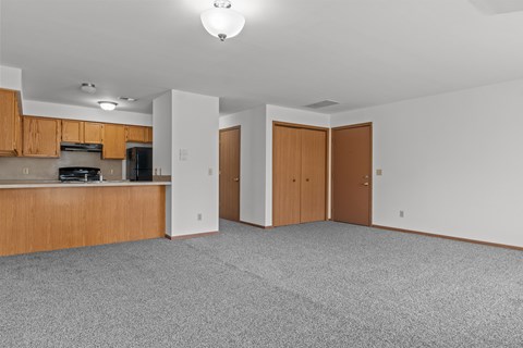 A kitchen with wooden cabinets and a grey carpet.