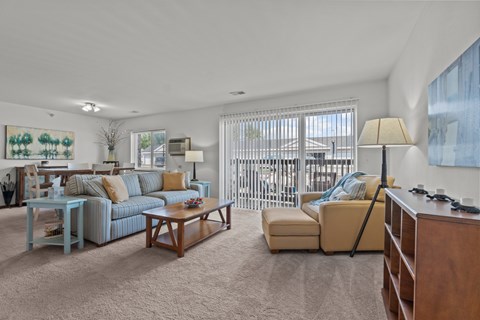A living room with a blue couch, a yellow couch, a wooden coffee table, and a painting on the wall.