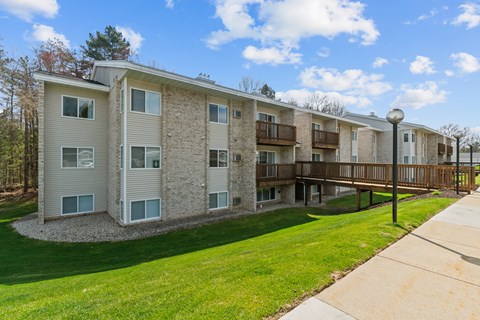 Apartment building with a grassy area in front and a sidewalk.