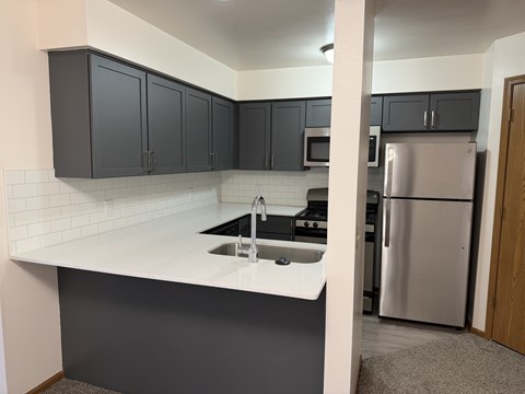 A kitchen with a white counter top and black cabinets.