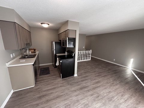 A kitchen with a refrigerator, microwave, and oven.