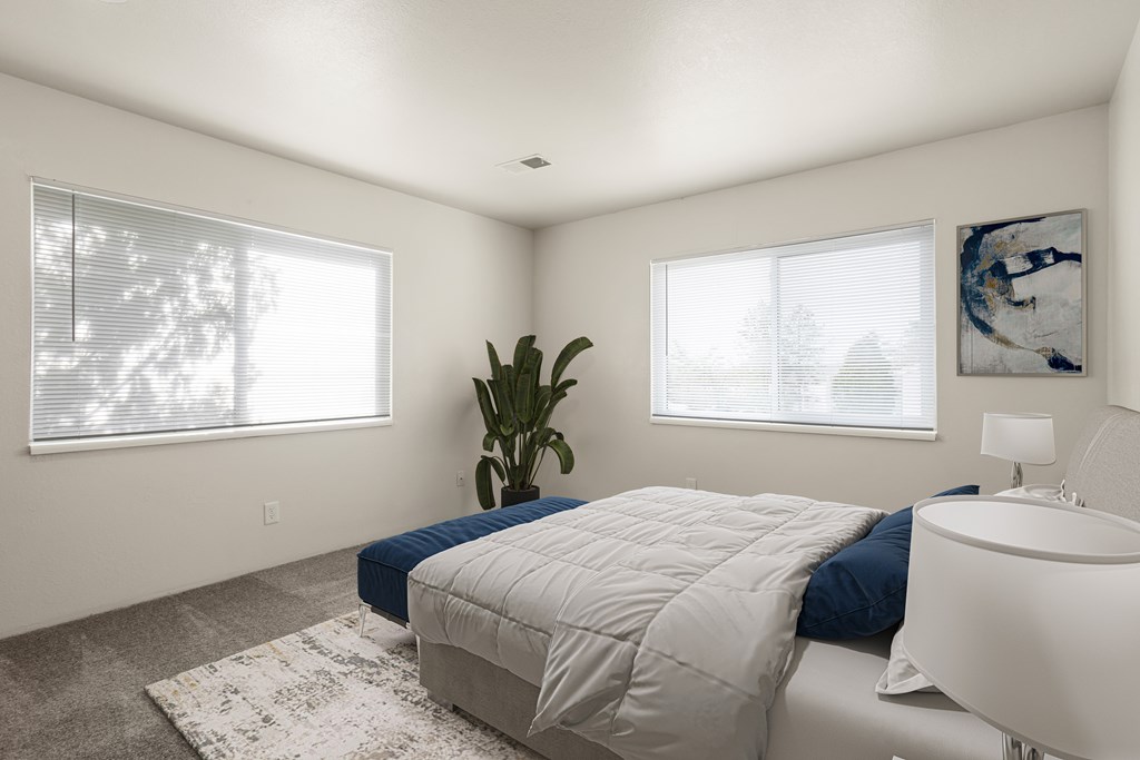A bedroom with a large bed and a plant.