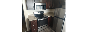 A kitchen with a stainless steel refrigerator, oven, and microwave.