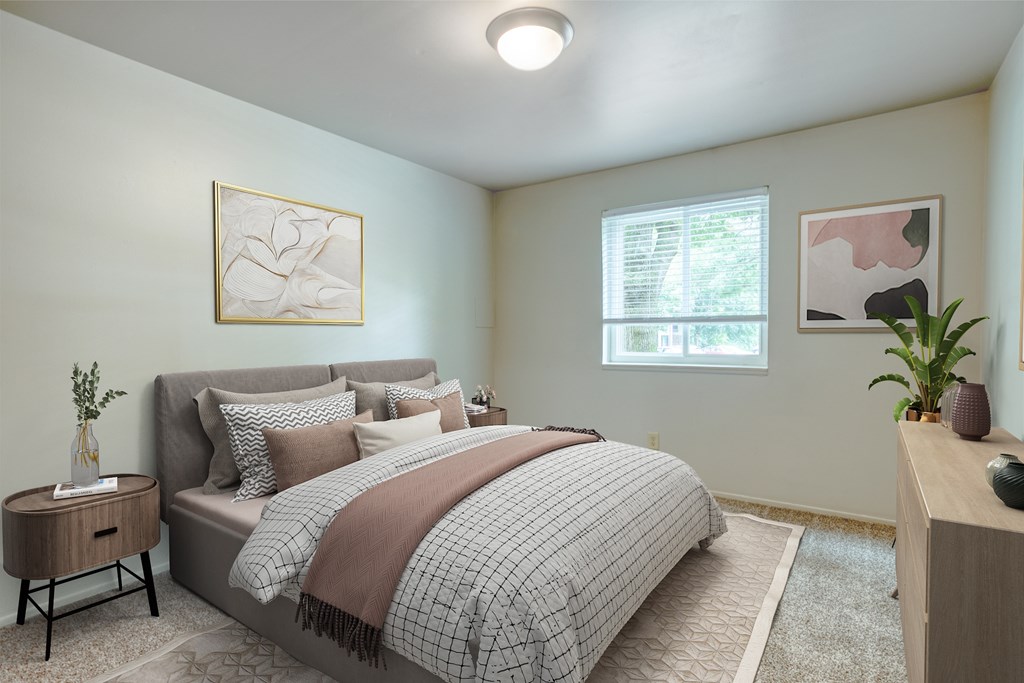 A bedroom with a bed, nightstand, and two framed pictures on the wall.