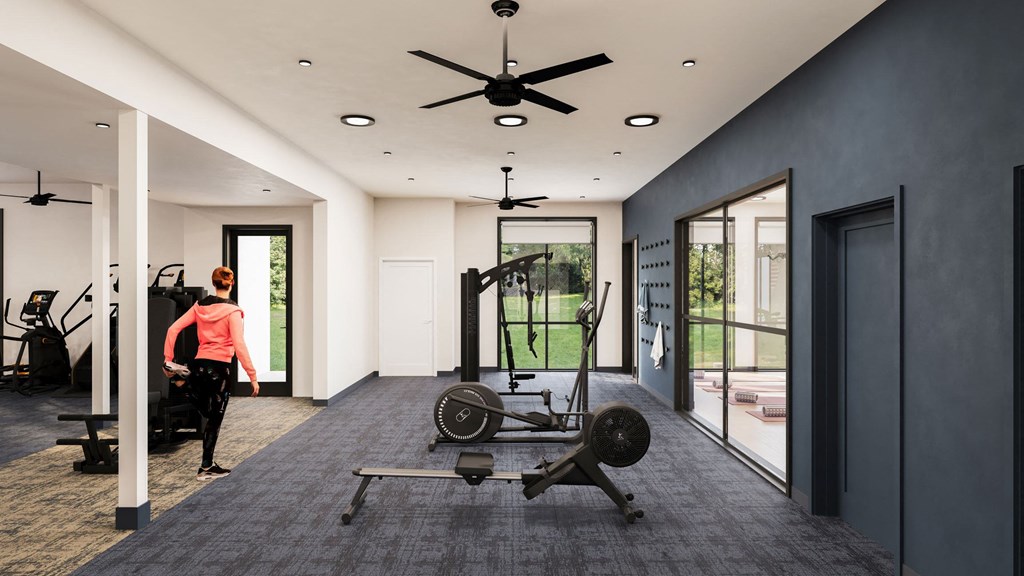 a woman walking in a gym with weights and a ceiling fan
