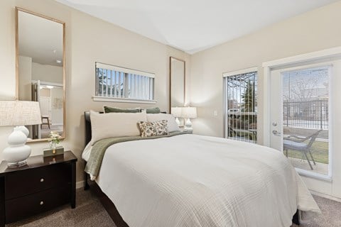 A bedroom with a large bed, a dresser with a mirror, and a window with blinds.