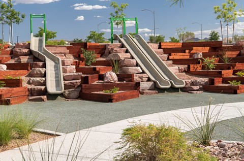a playground with slides and rocks and plants