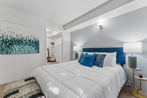 A bedroom with a white bed and blue pillows.