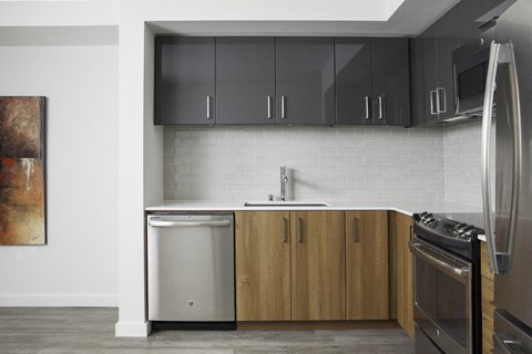 a kitchen with black cabinets and a stainless steel refrigerator