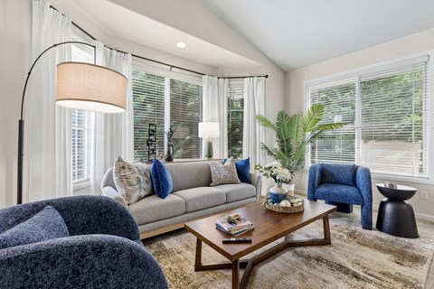 A living room with a grey couch, a blue armchair, a wooden coffee table, and a floor lamp.