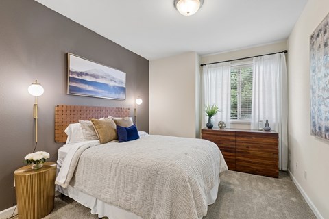 A bedroom with a large bed and a painting on the wall.