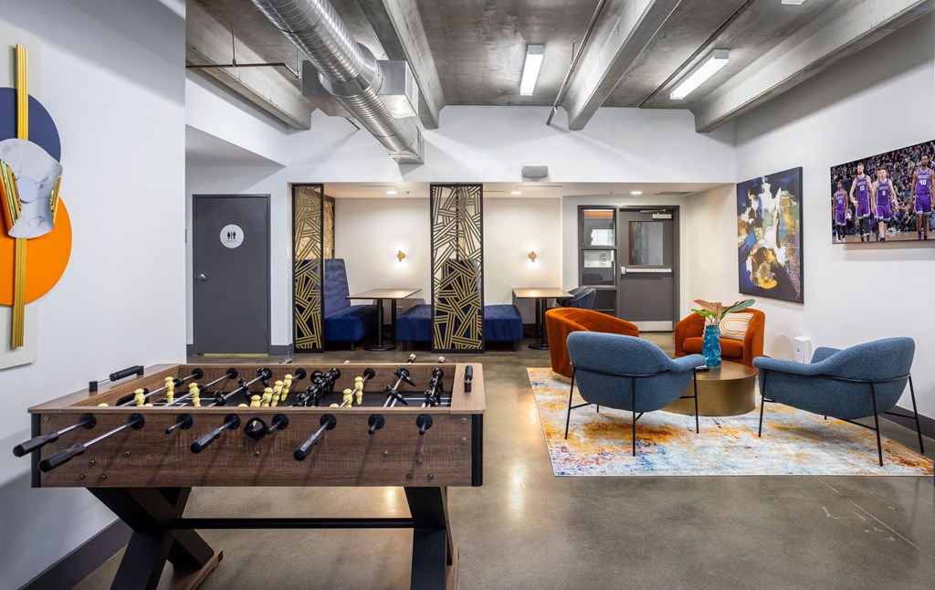 a living room with a foosball table and a game room with couches