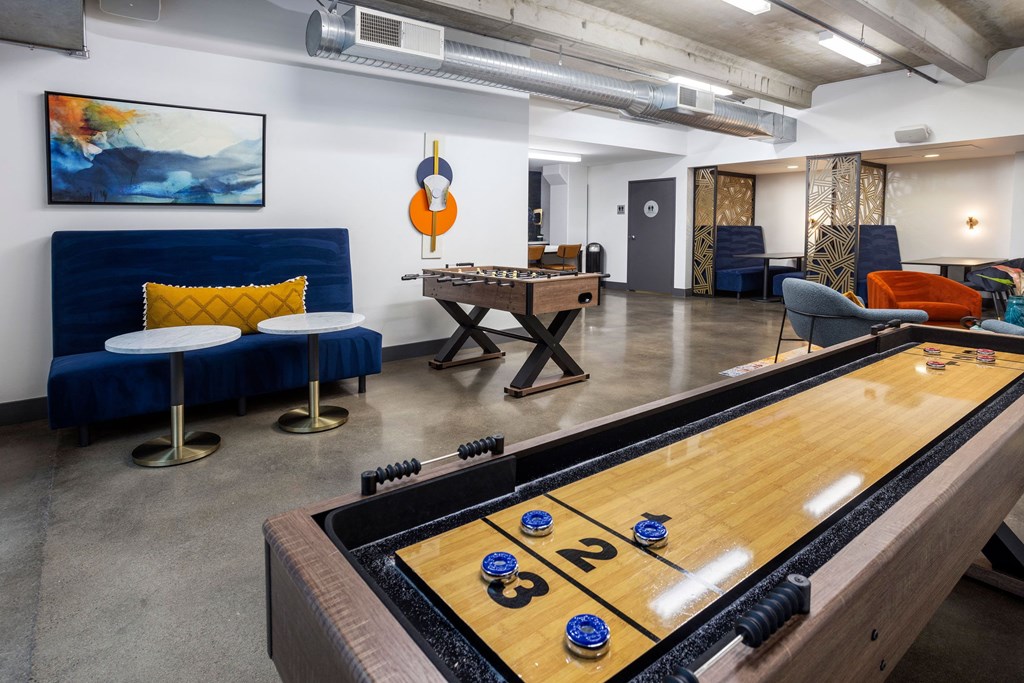 a game room with a shuffleboard table and a foosball