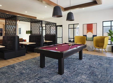 A pool table is in the middle of a room with a blue rug.