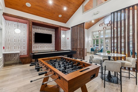 A shiny pool table is in the middle of a room with a bar and a television.