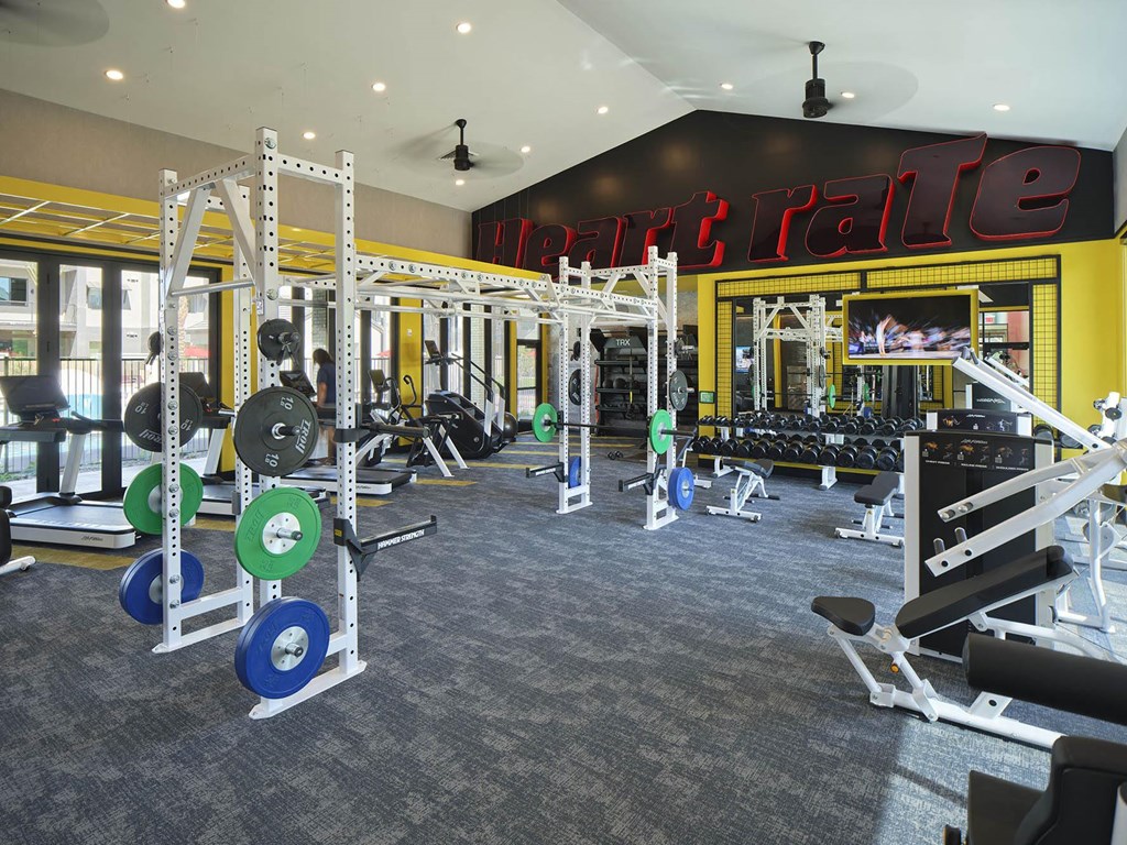 a gym with weights and cardio machines and a neon sign