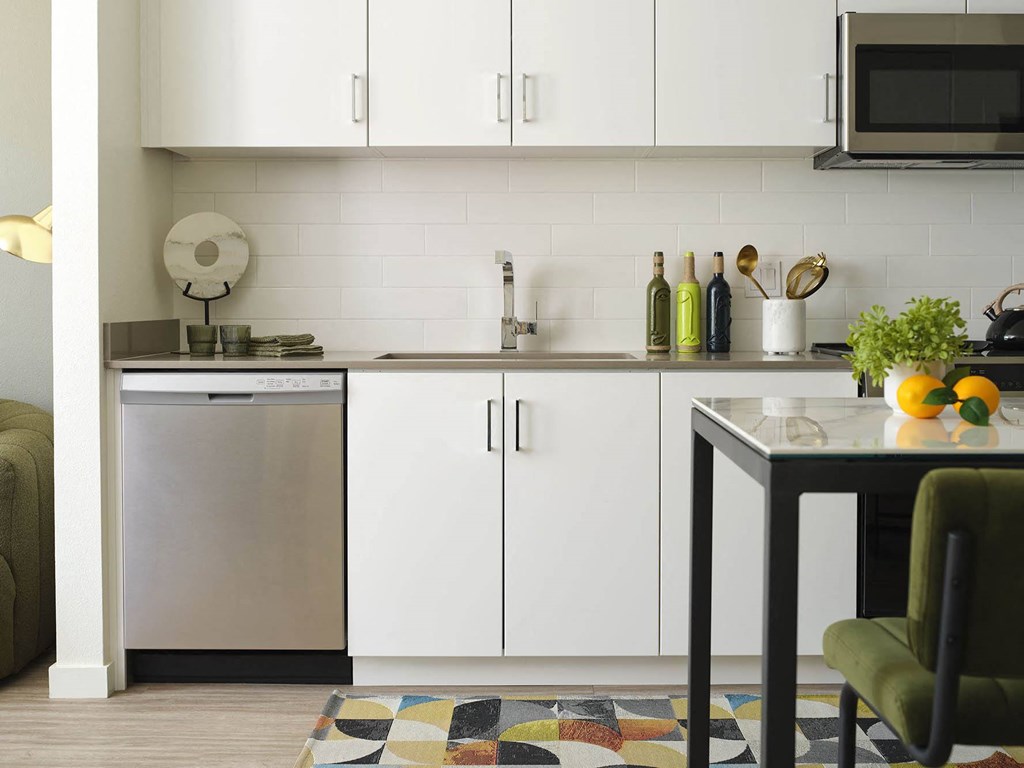 a small kitchen with white cabinets and a table