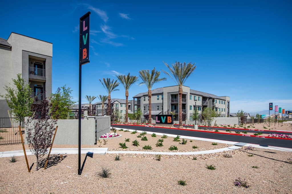 a street sign is in the middle of an empty street with buildings and palm trees