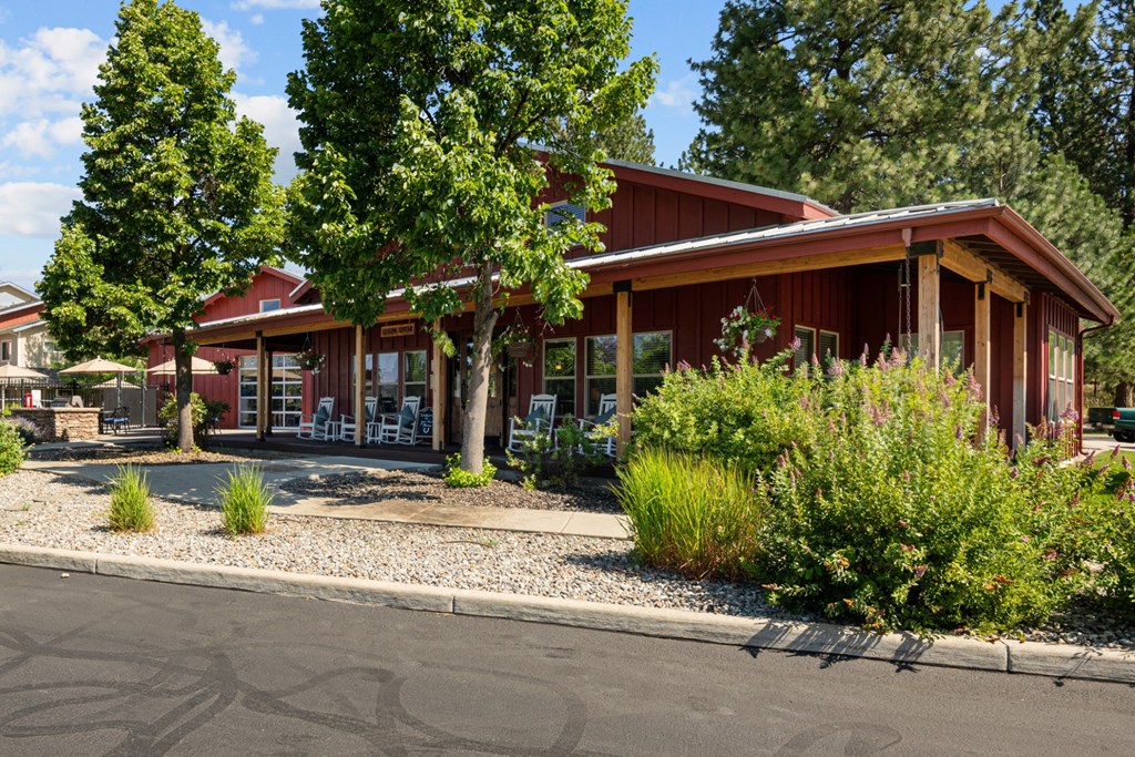 the front of a red building with trees and a street