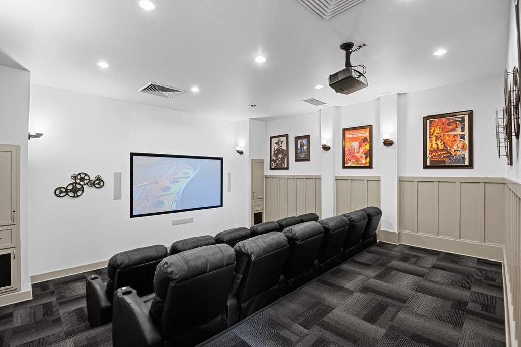 a theater room with a row of black chairs and a tv on the wall
