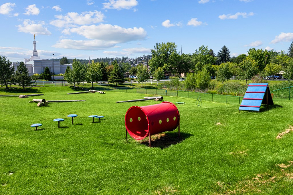 a playground with a seesaw and a red barrel in a field