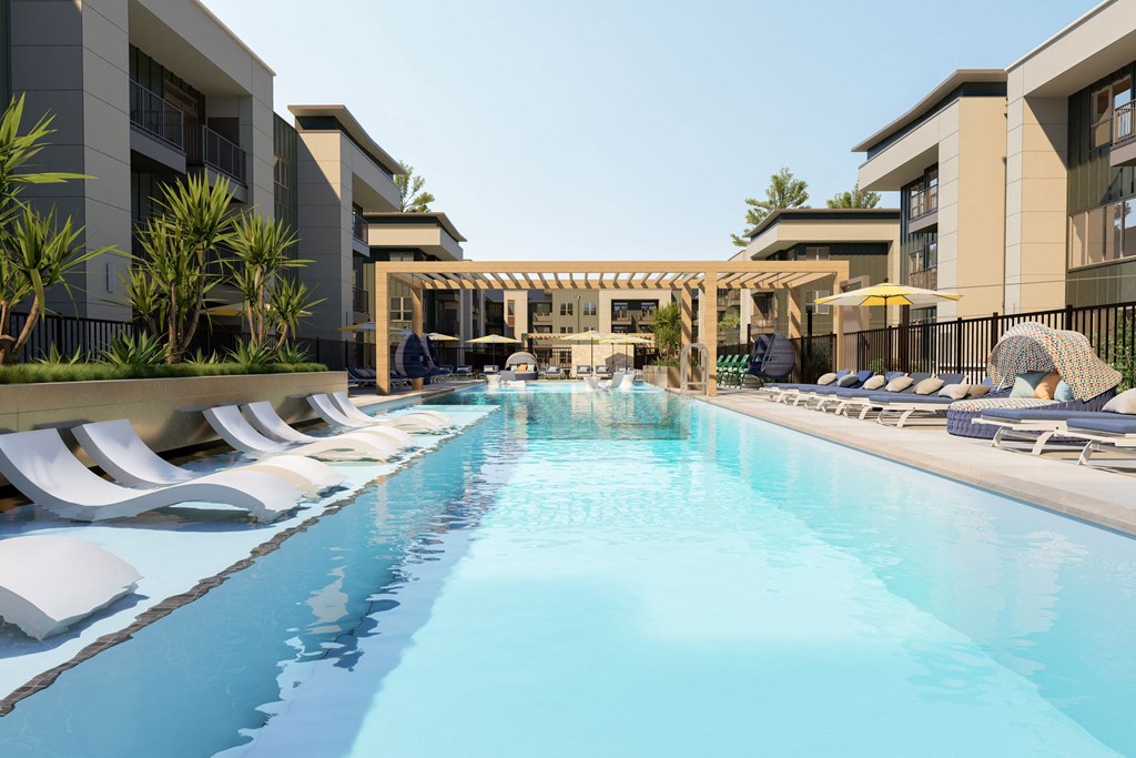 a large swimming pool with lounge chairs in front of a building
