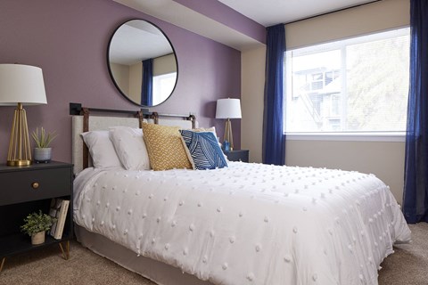 a bedroom with a white bed and purple walls and a mirror