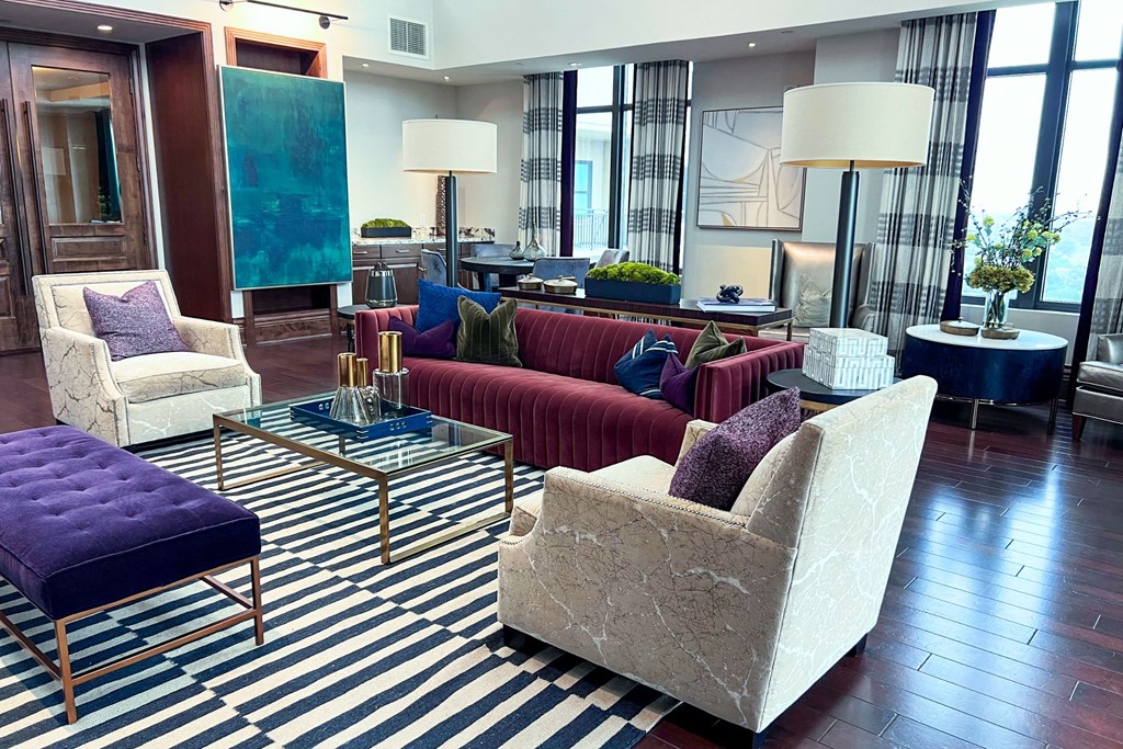 a living room with couches and chairs and a striped rug