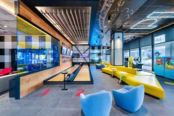a bowling alley in the lobby of a building with blue and yellow couches
