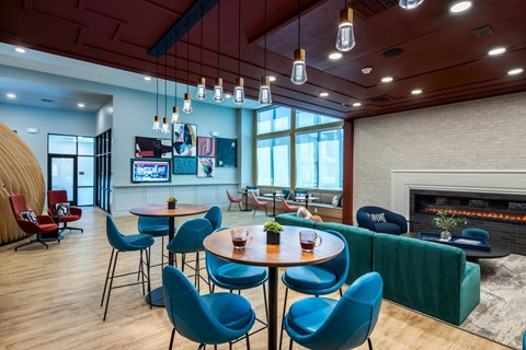 a lounge area with blue chairs and tables and a fireplace