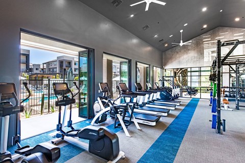 a gym with cardio equipment and windows with a view of a building