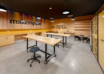 a communal table in a maker space with desks and chairs