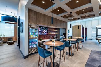 a lobby with tables and chairs and a bar with a television