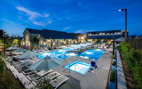 a swimming pool with chairs and umbrellas at night