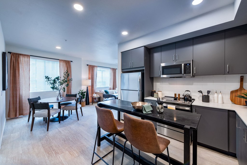 a kitchen with a island and a dining room with a table and chairs